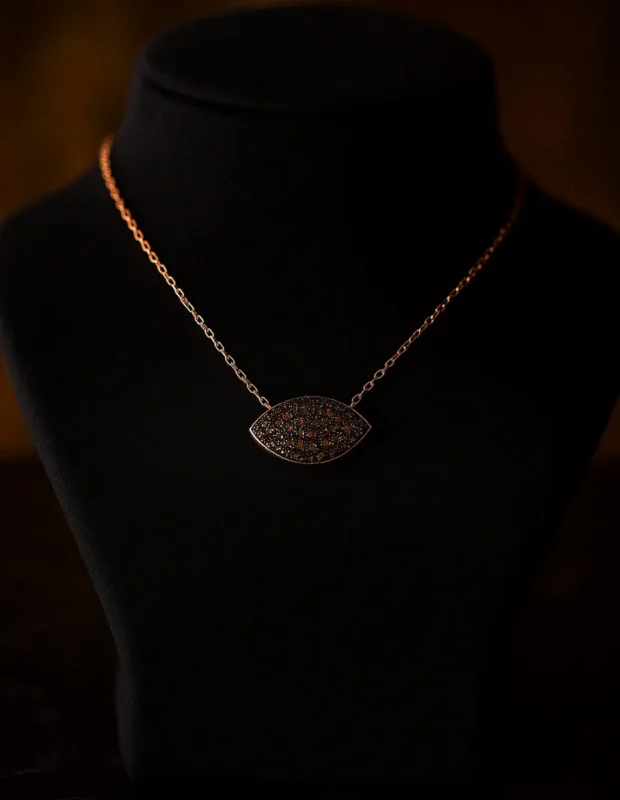 Siyah manken büstünde sergilenen siyah taşlı rose gold göz kolye.