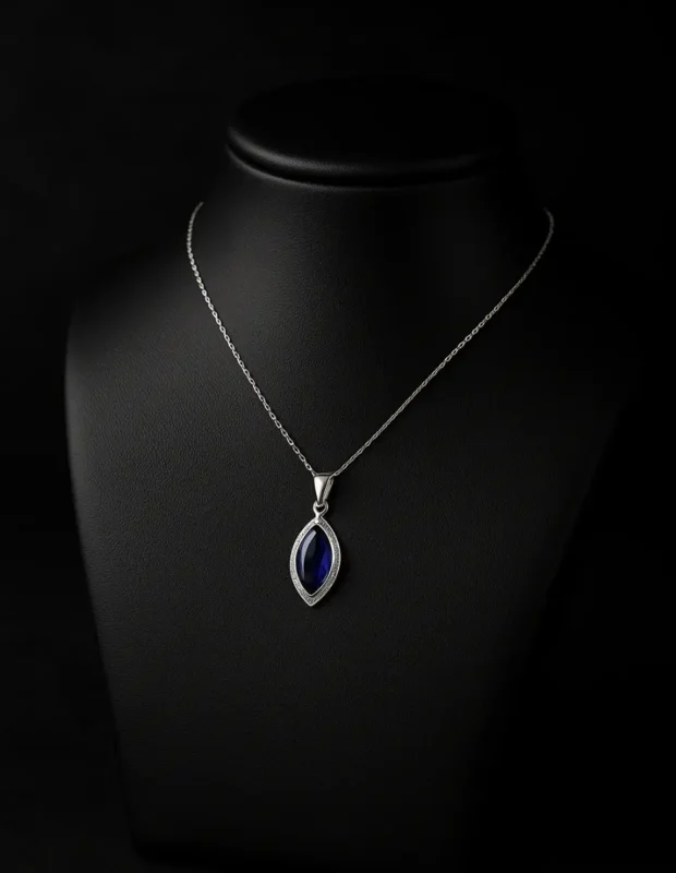 Siyah manken büstünde sergilenen mavi taşlı mekik kesim gümüş kolye.